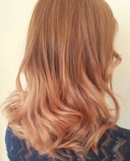 Balayage long hair: back view of a woman with long wavy strawberry blonde balayage hair