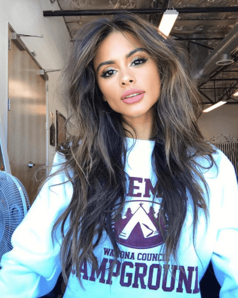 long dark brown haired model with blonde highlights framing the face while wearing logo jumper
