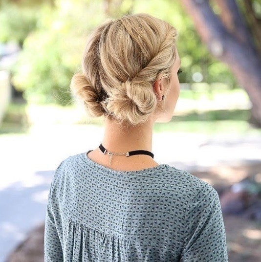 blonde woman wearing a blue patterened top with her hair in twisted low macaron buns