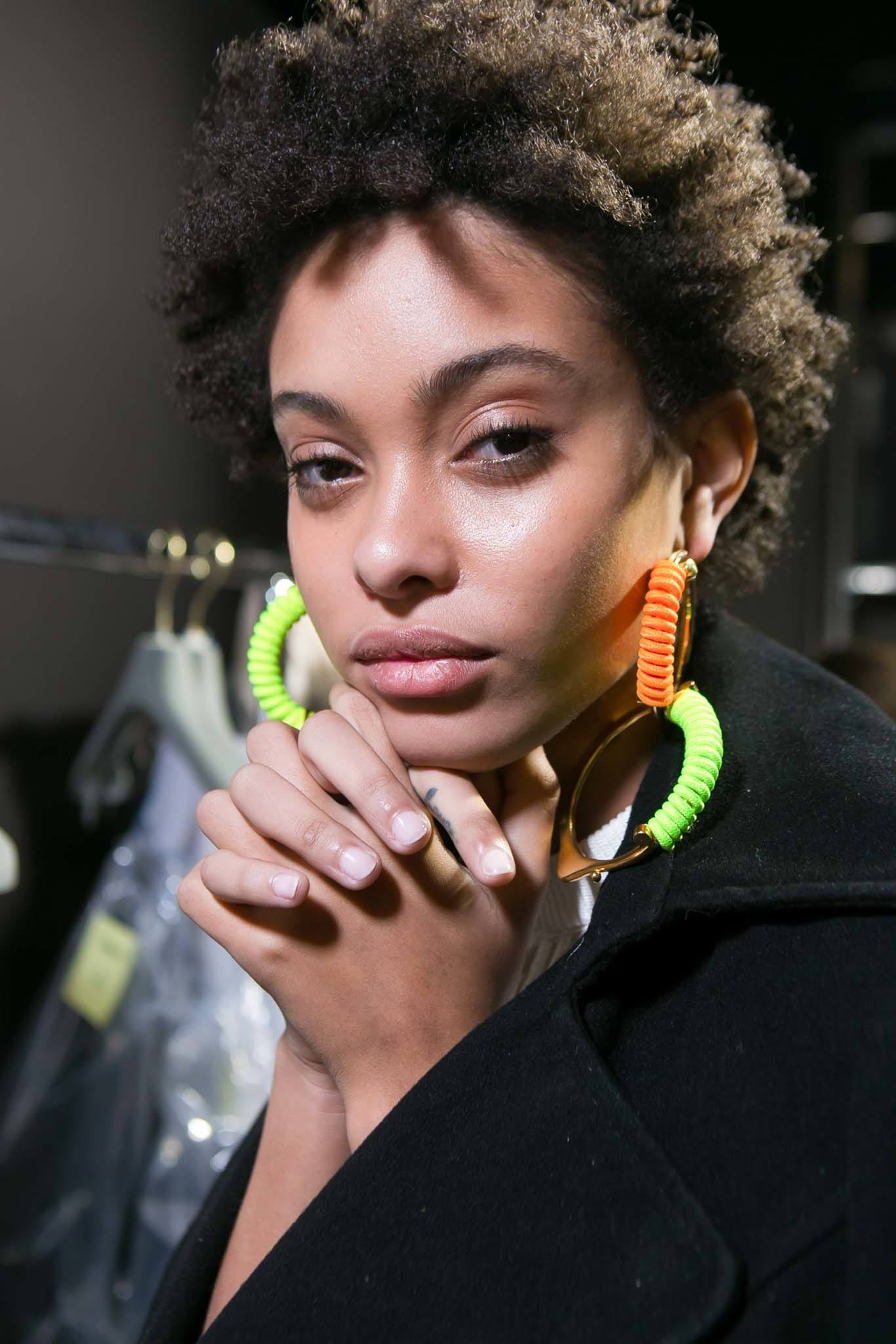best leave in conditioner for dry hair: backstage shot of model with short afro hair backstage posing
