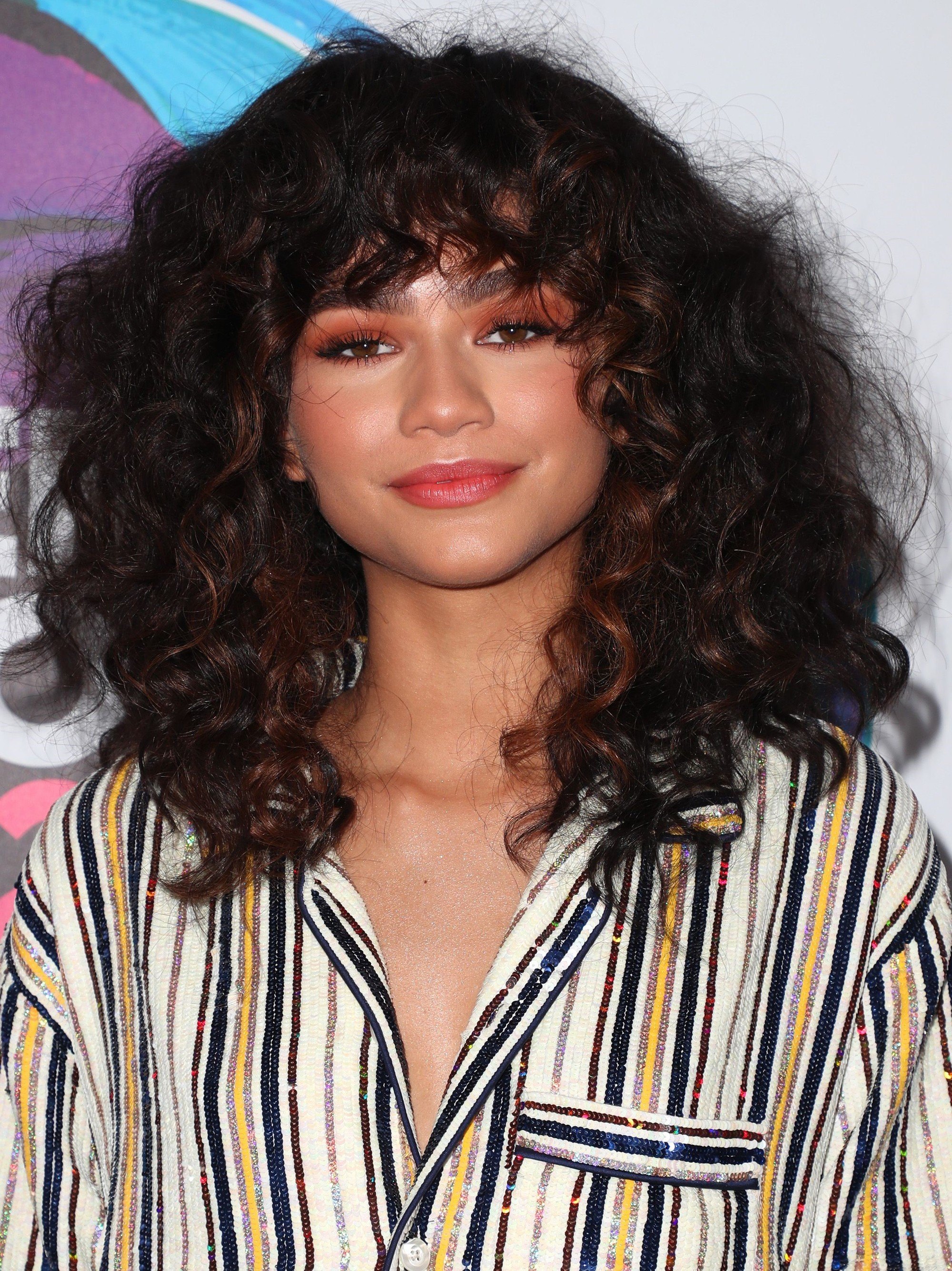 the best bangs directory: close up shot of zendaya with curly bang hairstyle on the teen choice awards red carpet, wearing glittery outfit