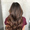 back shot of a woman with long curly chestnut brunette hair with auburn highlights