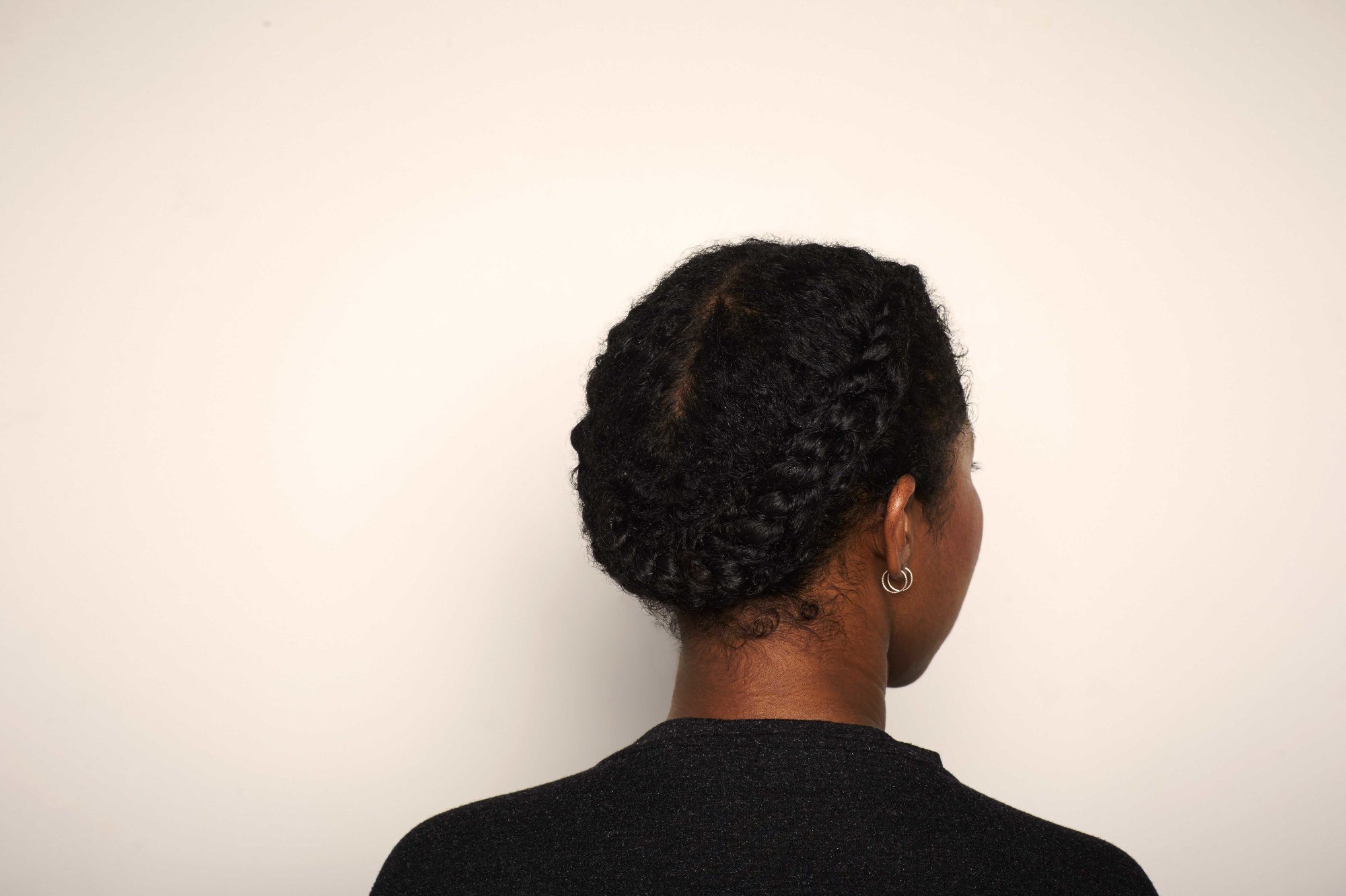 back shot of a woman with her afro hair in a flat twist halo braid style