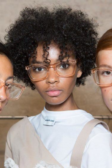 Anti-frizz spray: Models backstage with straight and natural curly hair in different lengths and colours all wearing glasses.
