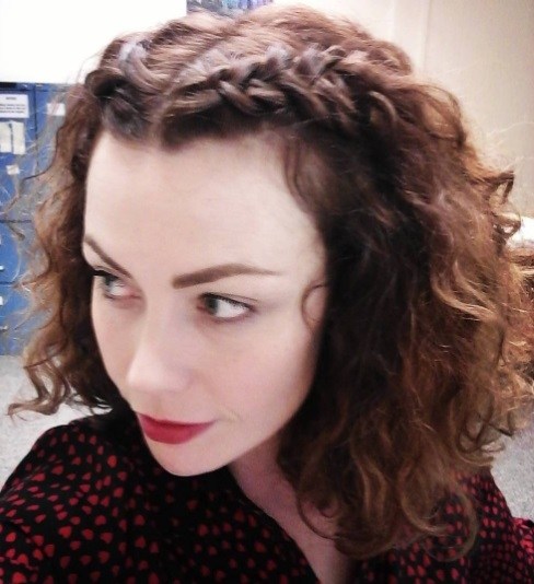 selfie of a woman with curly frizzy hair with half up braids
