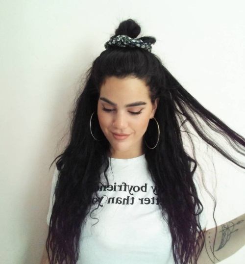 woman with dark brunette long hair in a half up bun tied with a scrunchie