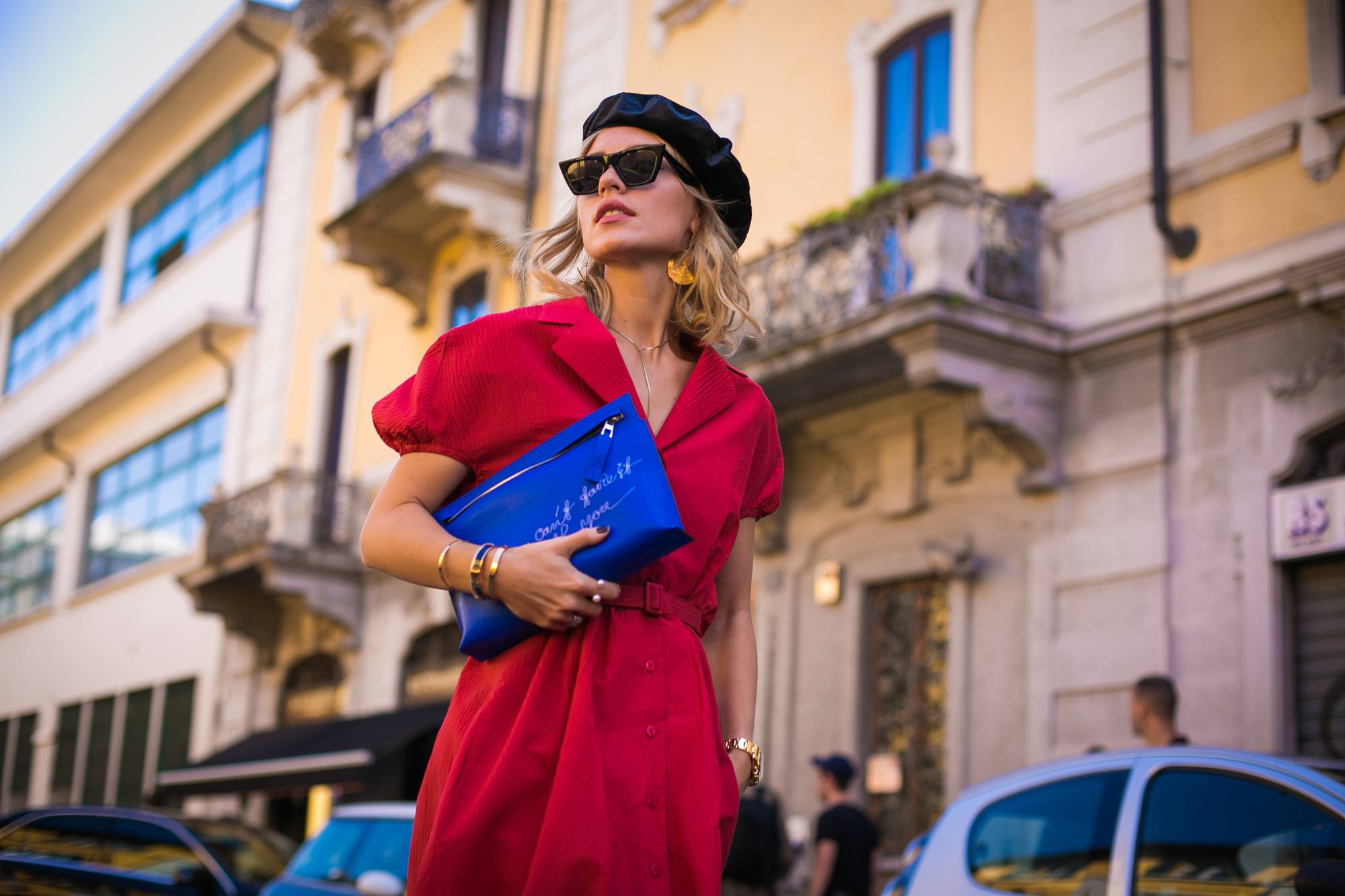Milan Fashion Week Street Style FW19: Woman with short blonde shoulder length hair wearing a black beret, sunglasses and a red dress