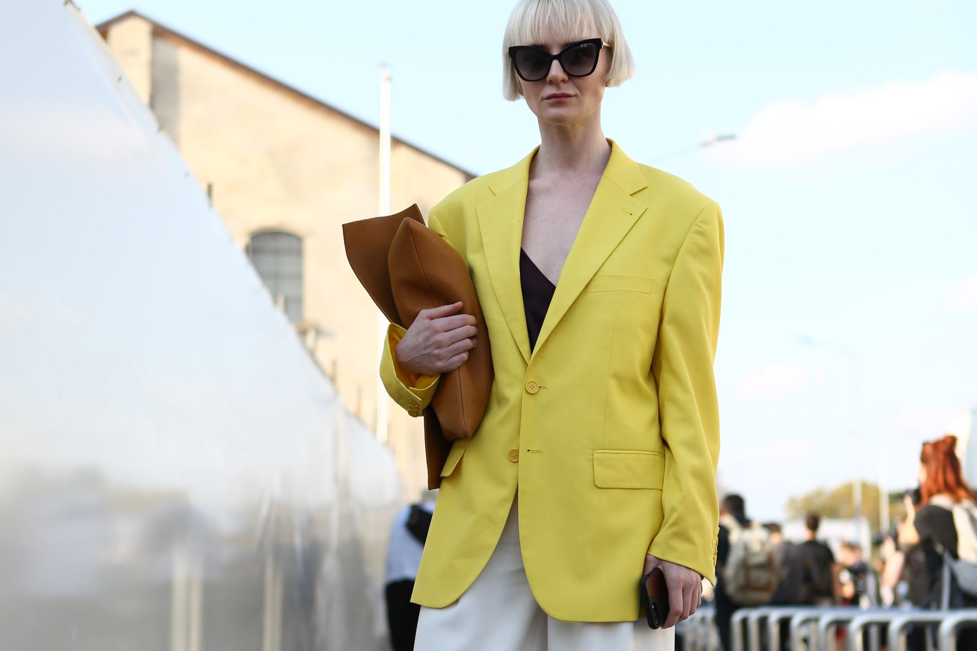 Milan Fashion Week Street Style FW19: Woman with short blonde bob with bangs wearing sunglasses and a yellow blazer.
