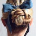 back view of blonde hair in low braided bun with ribbon wrapped around