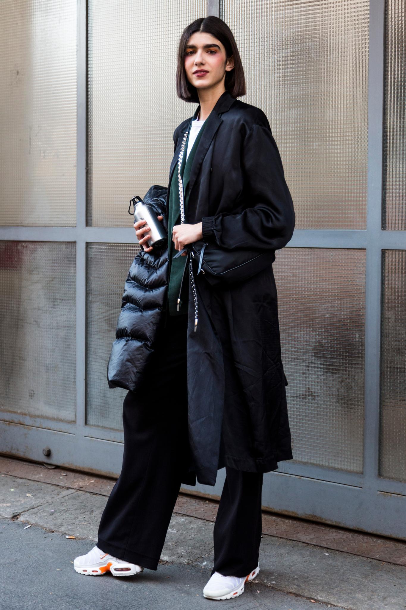 Milan Fashion Week Street Style: Woman with dark brown straight bob wearing black long coat.