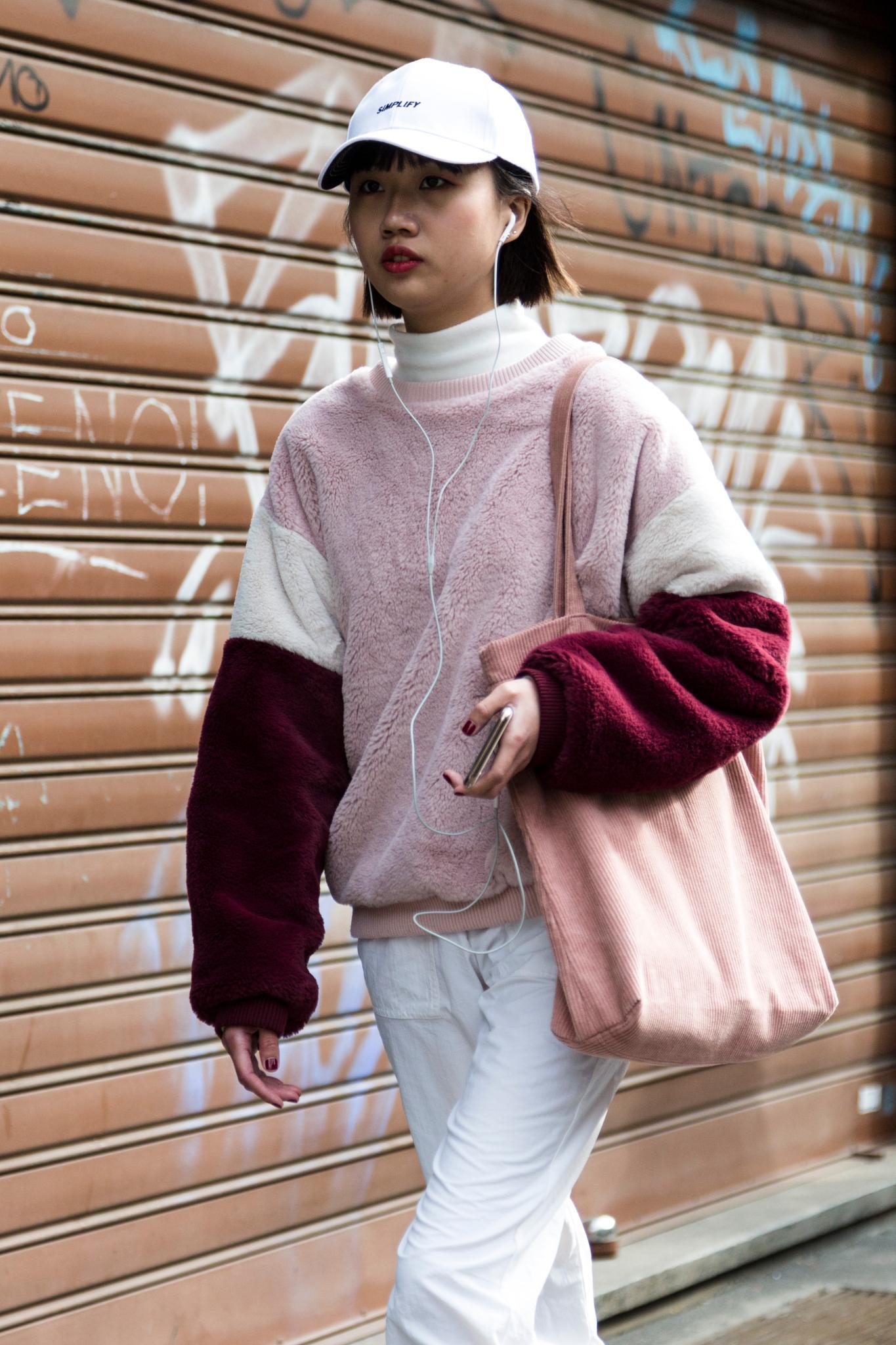 Milan Fashion Week Street Style: Woman with dark brown blunt bob wearing a white baseball cap and pink toned sports outfit.