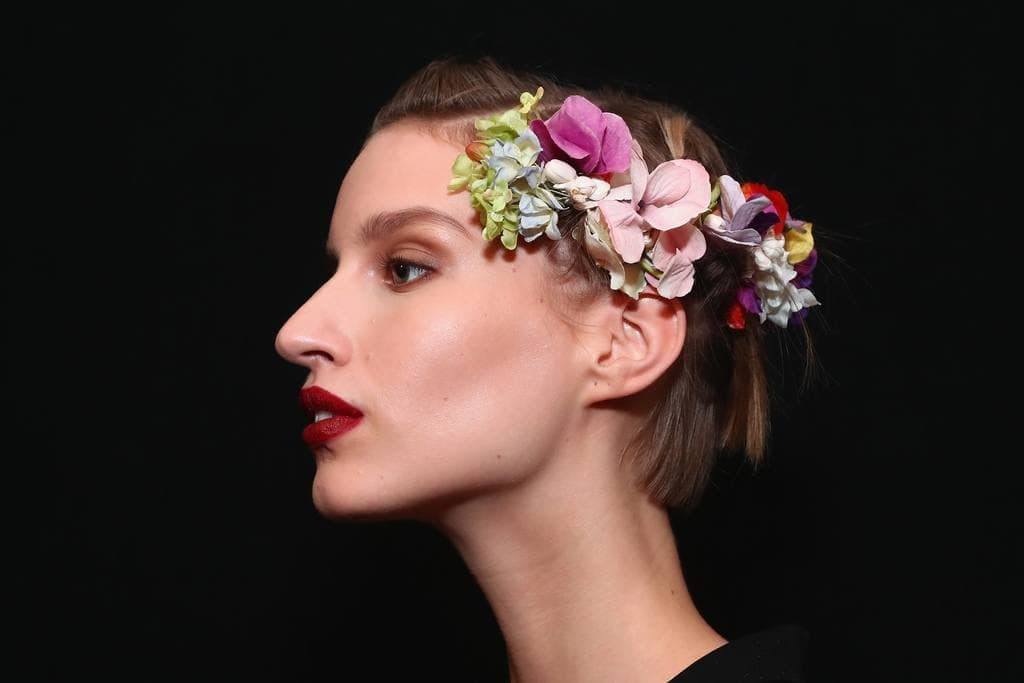 woman backstage at the naeem khan ss18 show with flowers in her short blonde hair