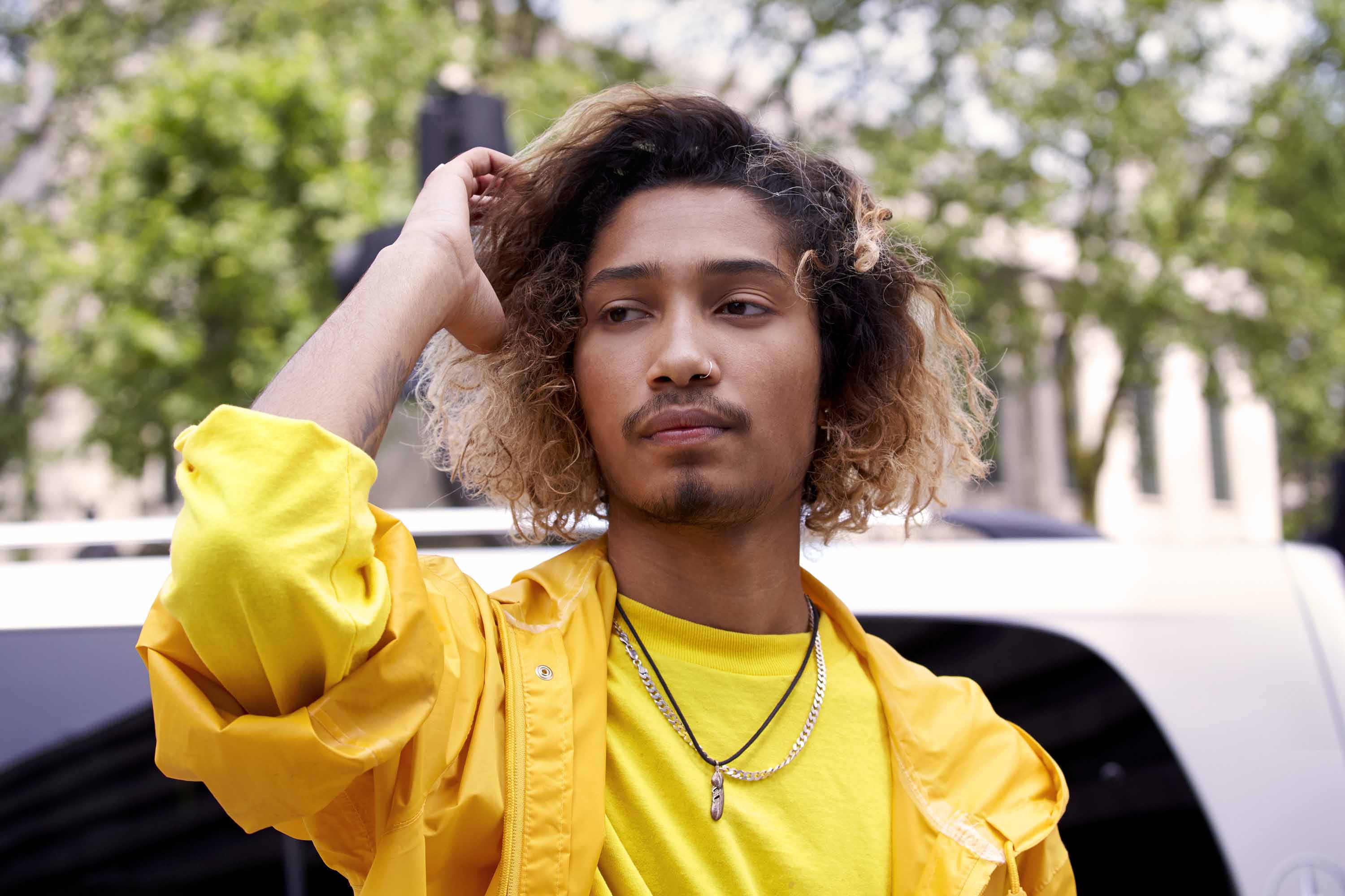 man in a yellow jacket running hands through his ombre beach wavy hair