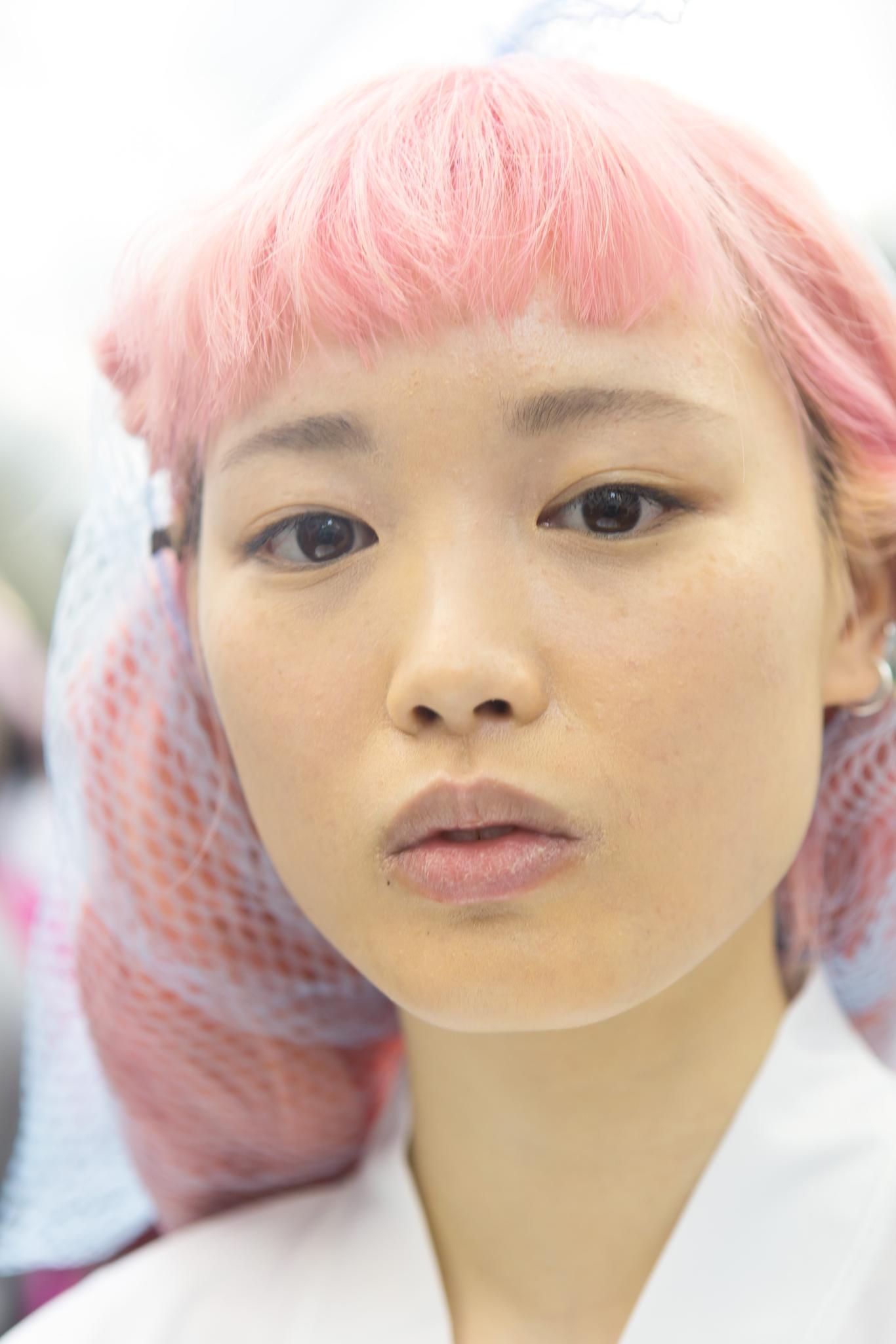 close up shot of model with pink hair in net backstage at a show