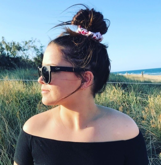 side profile of a brunette woman with her hair in a bun tied with a scrunchie