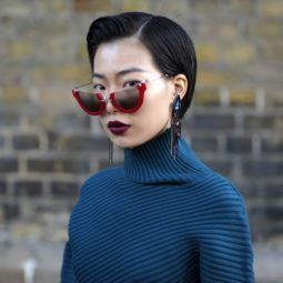 asian short hairstyles: close up shot of woman with short side-part pixie cut wearing blue jumper
