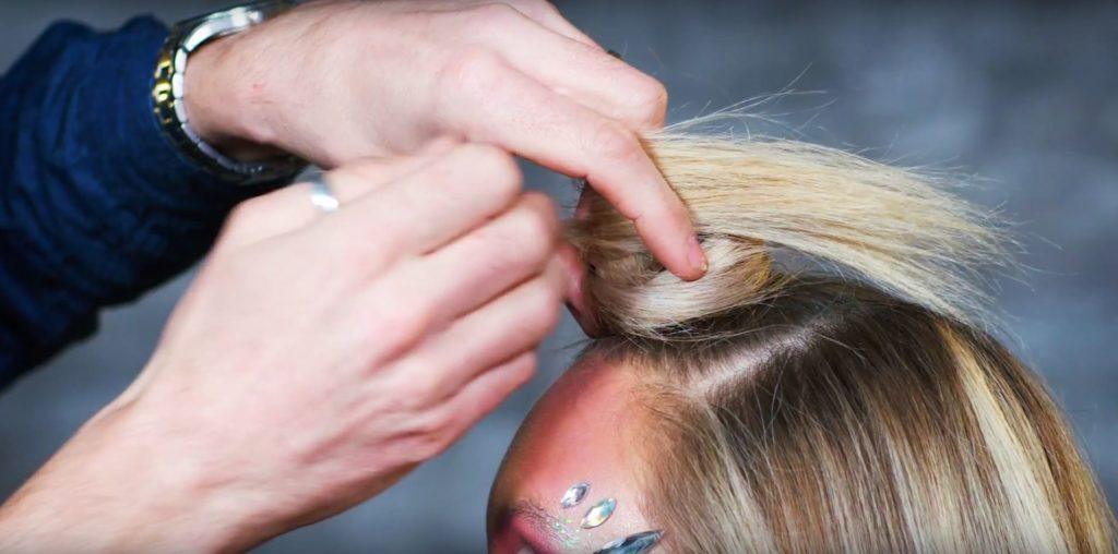 Unicorn Halloween tutorial: Close-up of a hair stylist shaping a unicorn horn on a blonde model.