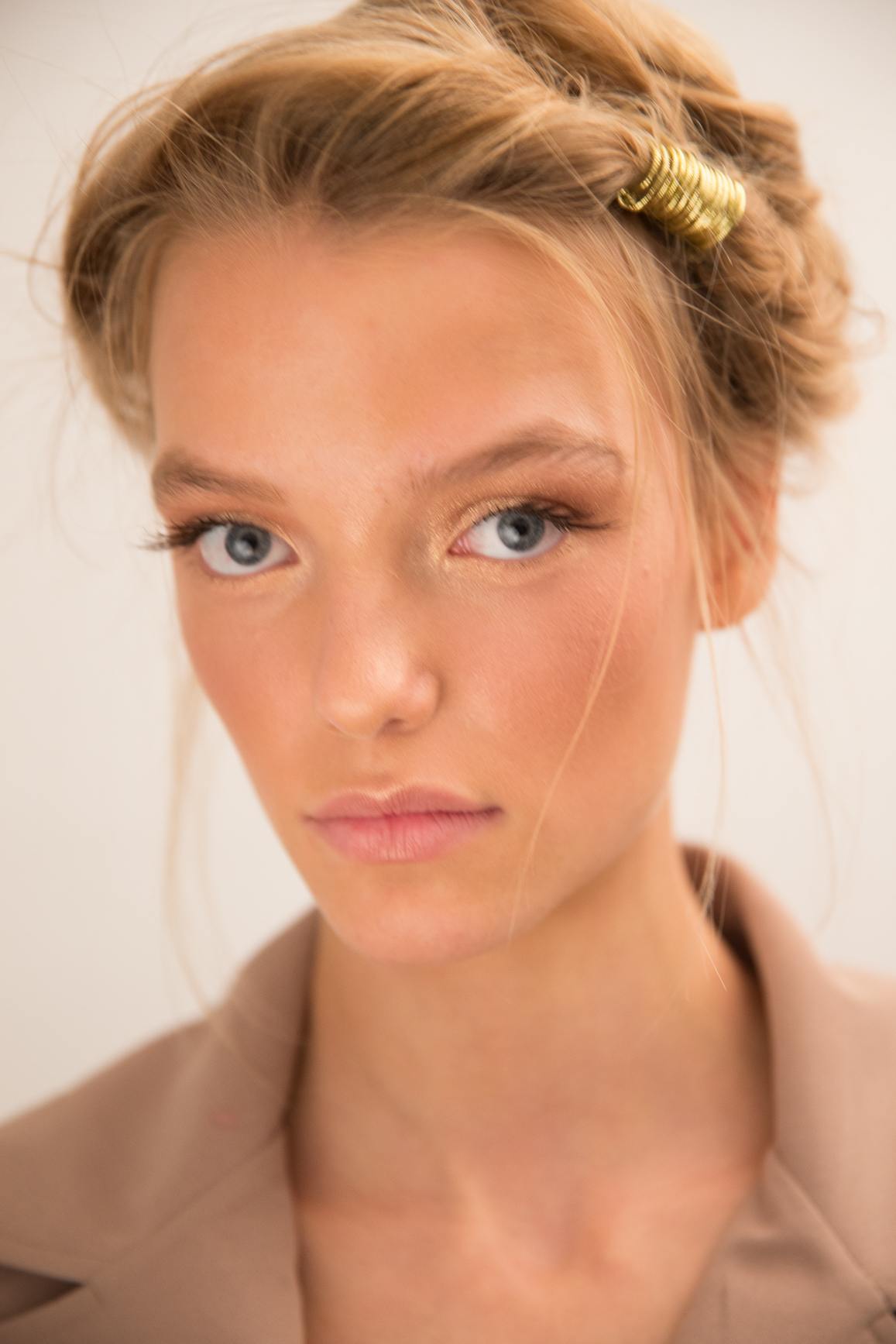 close up shot of model with twist updo with golden hair accessory into it with natural make up