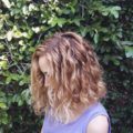 side profile picture of a woman with bob length copper balayage curly hair