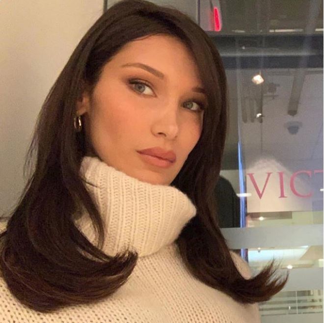 Fall hair colours: Bella Hadid with chocolate brown medium length hair wearing a high neck cream knit jumper.