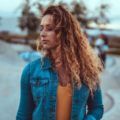 photo of a woman in a denim jacket and mustard top with curly ginger hair