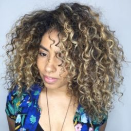 woman with brunette curly afro hair with blonde balayage