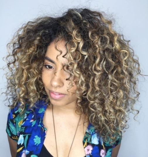 woman with brunette curly afro hair with blonde balayage