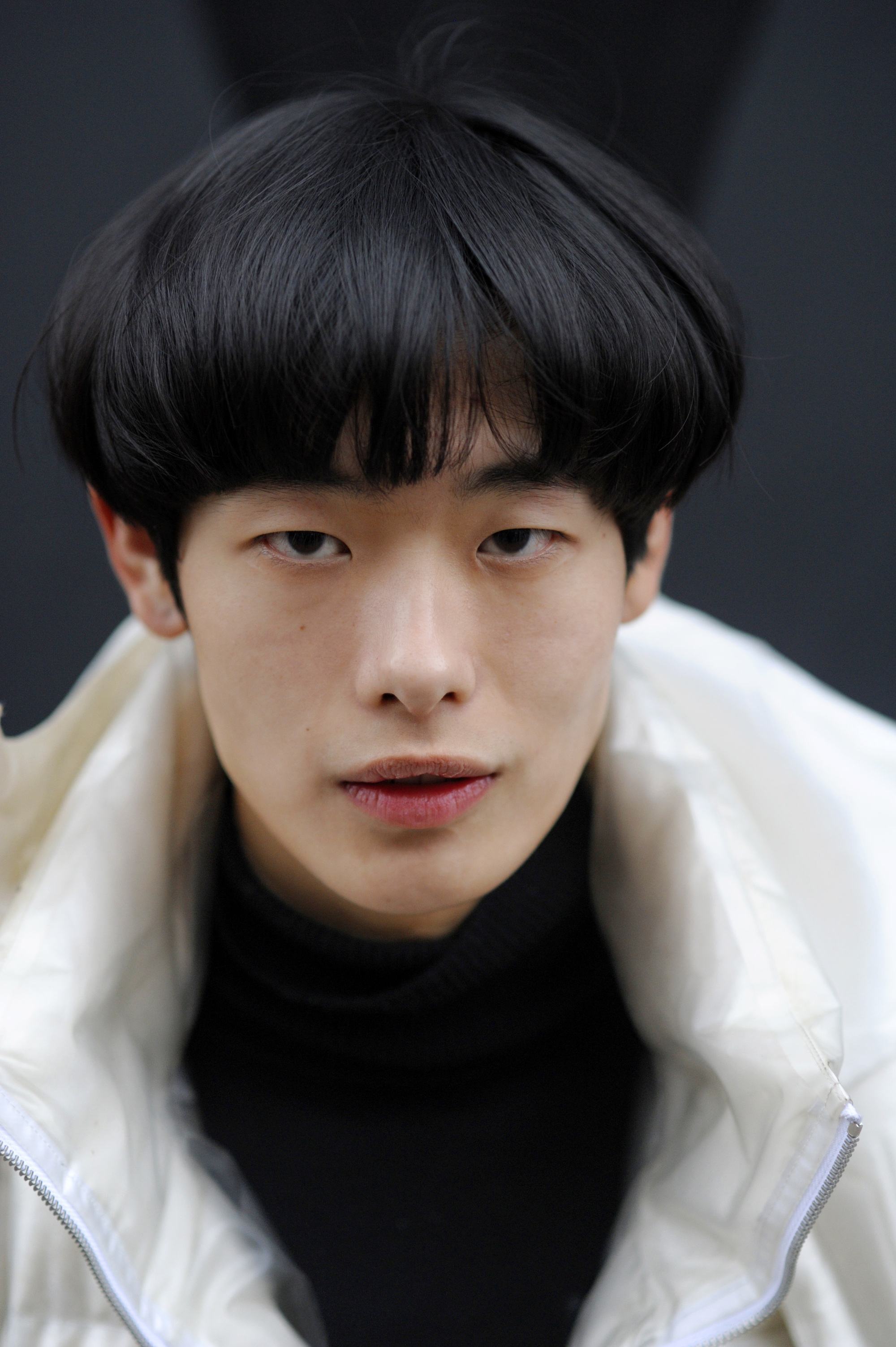 Vintage hairstyles for men: Close up shot of a man with dark brown medium bowl haircut, wearing black and shearling coat