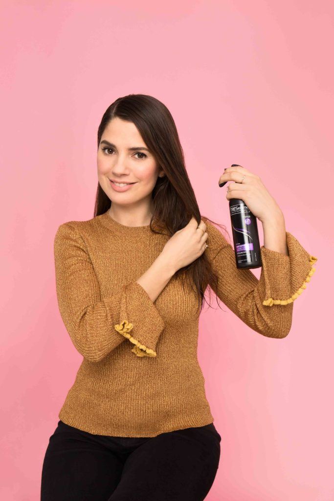 a woman spraying her long brunette hair