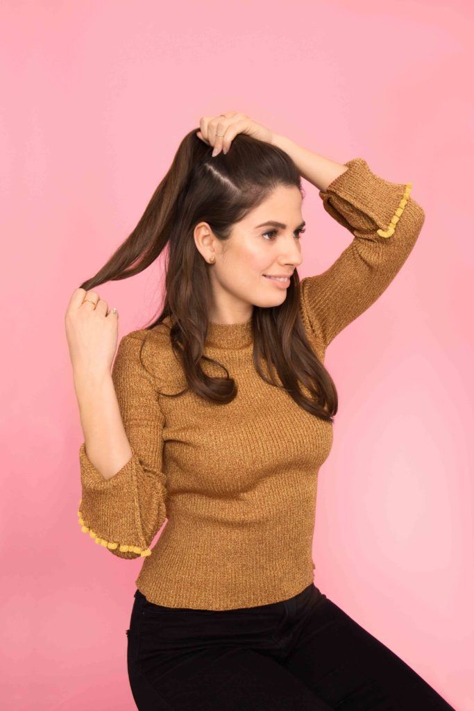 model creating a half ponytail hairstyle
