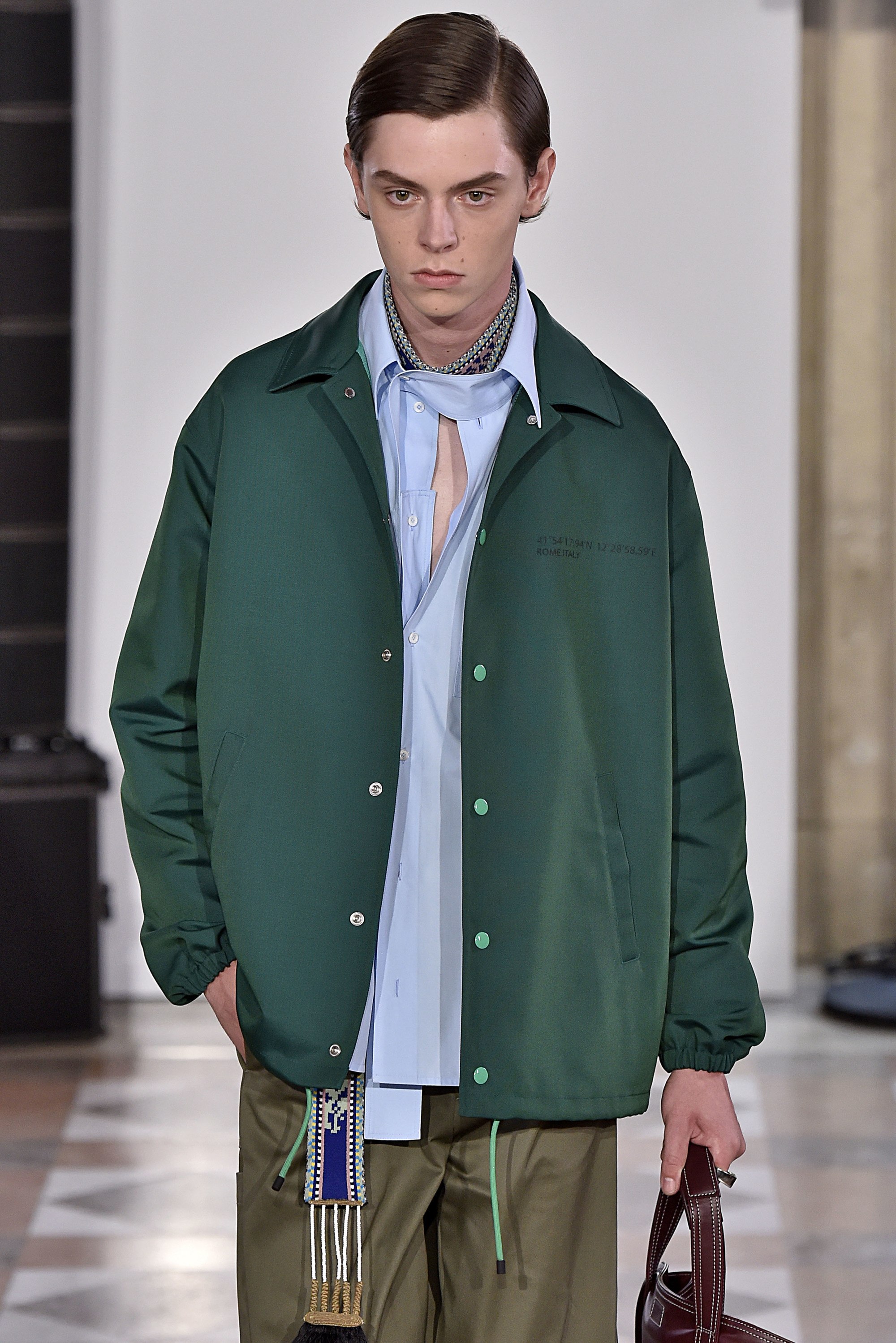brunette male model on the runway wearing a green jacket with side sweep hair