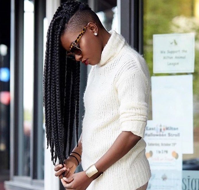 shot of woman with long box braids with shaved back and sides, posing on the street