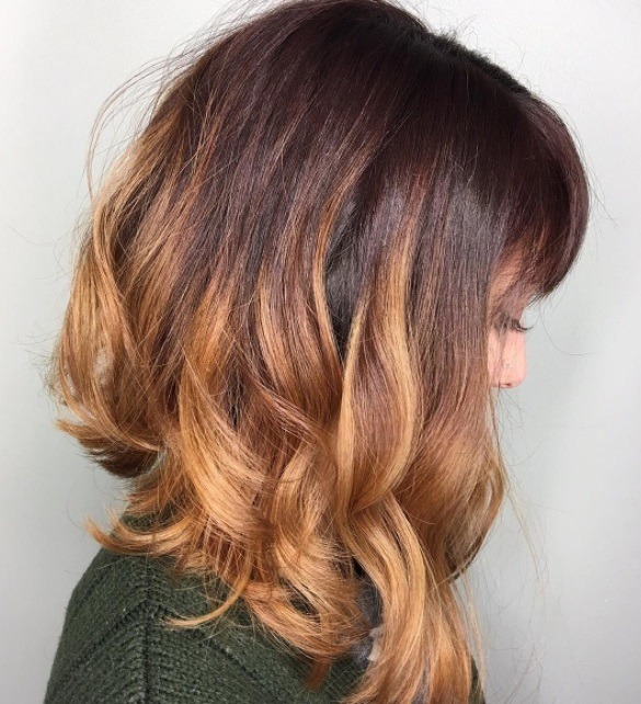 close up shot of woman with pumpkin ombre hair and long a line with bangs style at salon