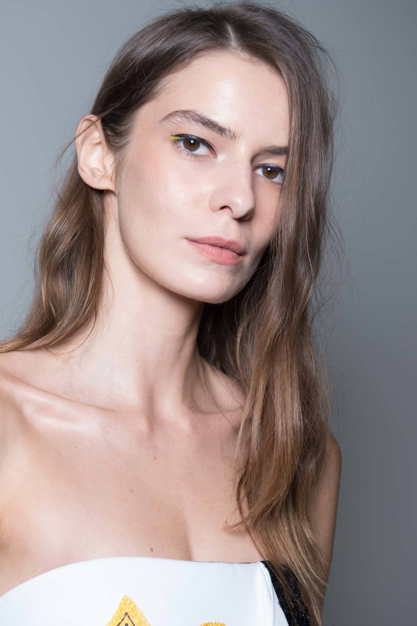 backstage shot of model with straight hair that has a few waves in it, posing