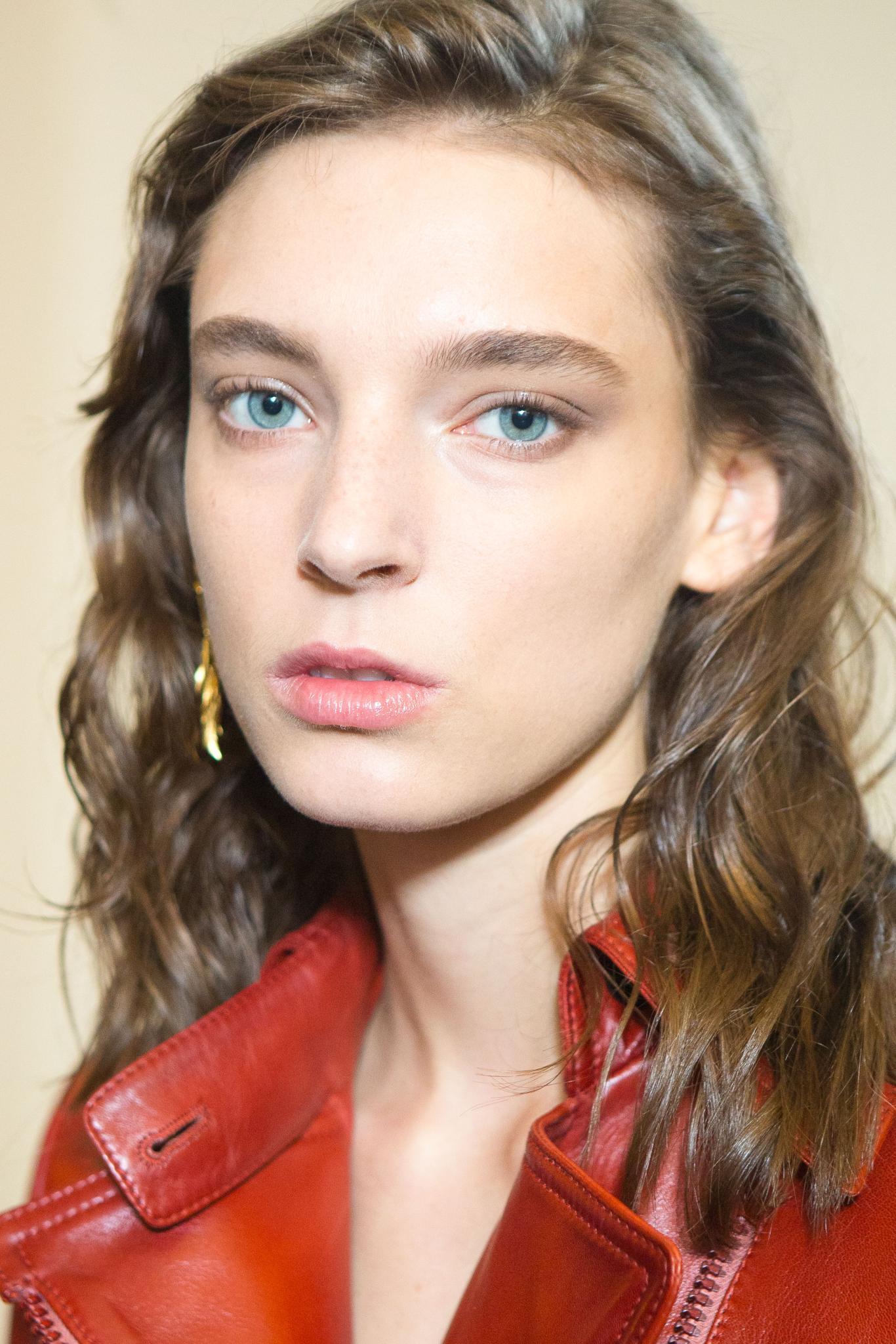close up shot of model with 2B hair, wearing red shirt and gold earrings, posing