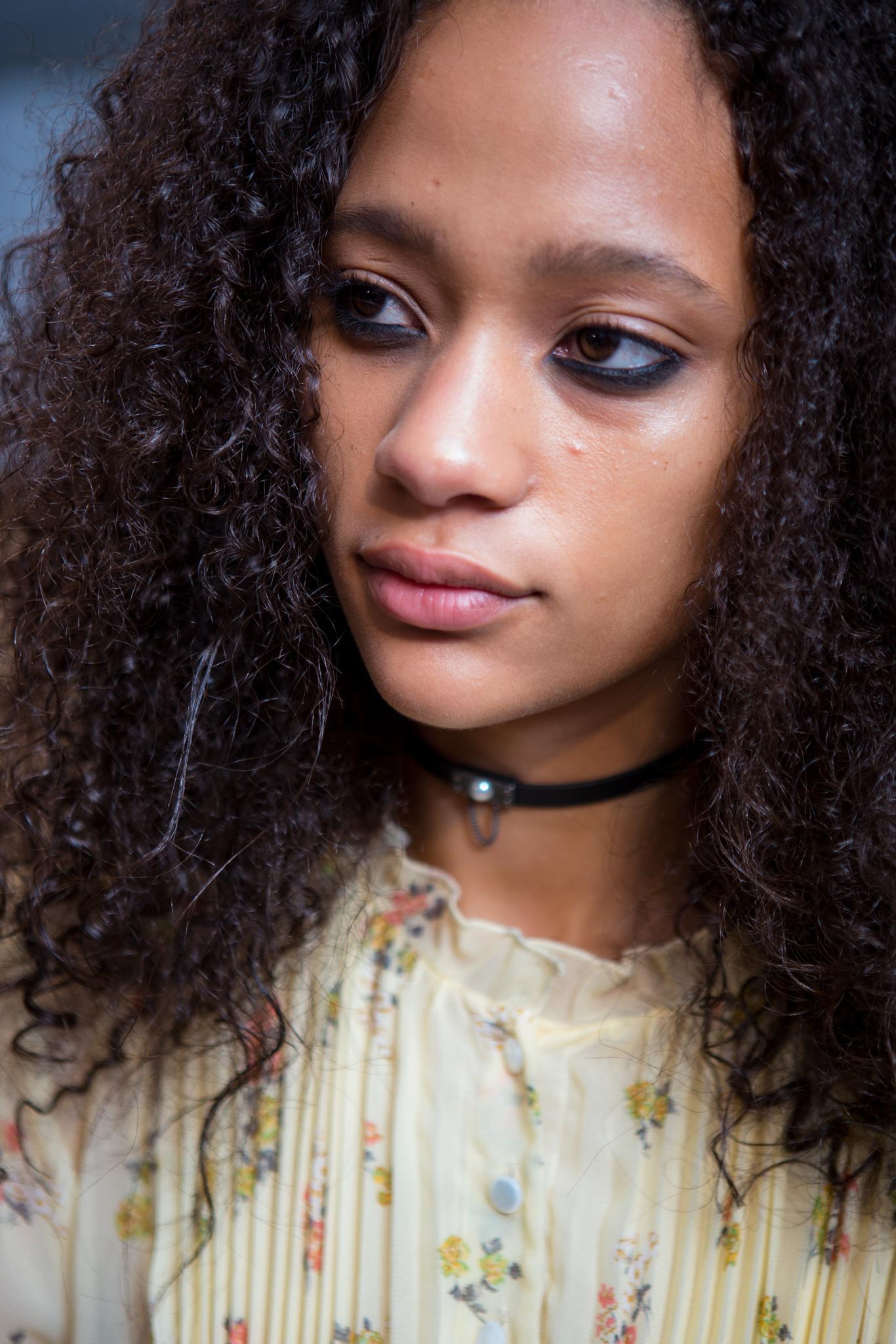 backstage shot of model with long curly hair with a choker, wearing a flora