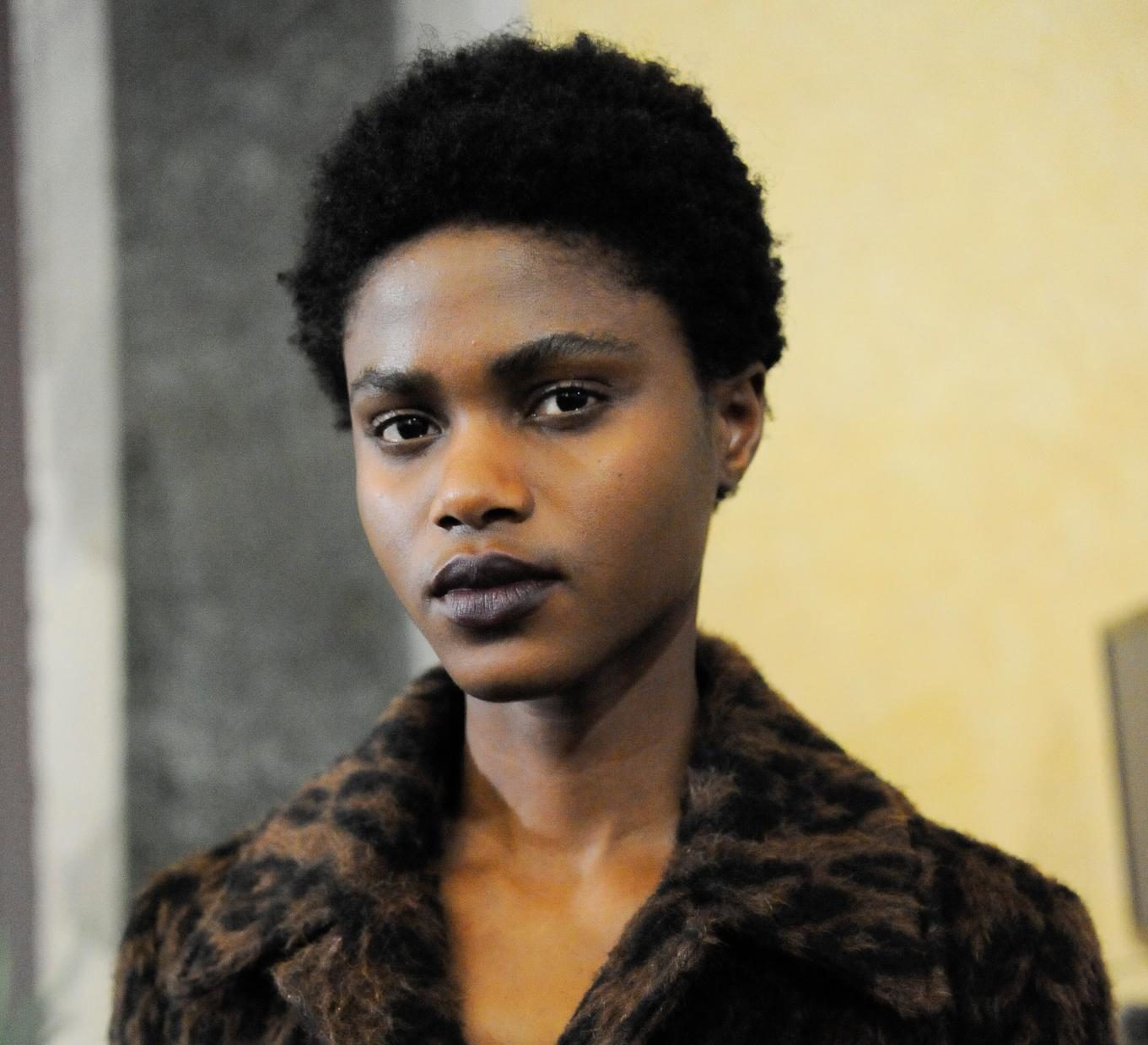 curly hair type quiz: backstage shot of model with jacket and short afro hairstyle posing