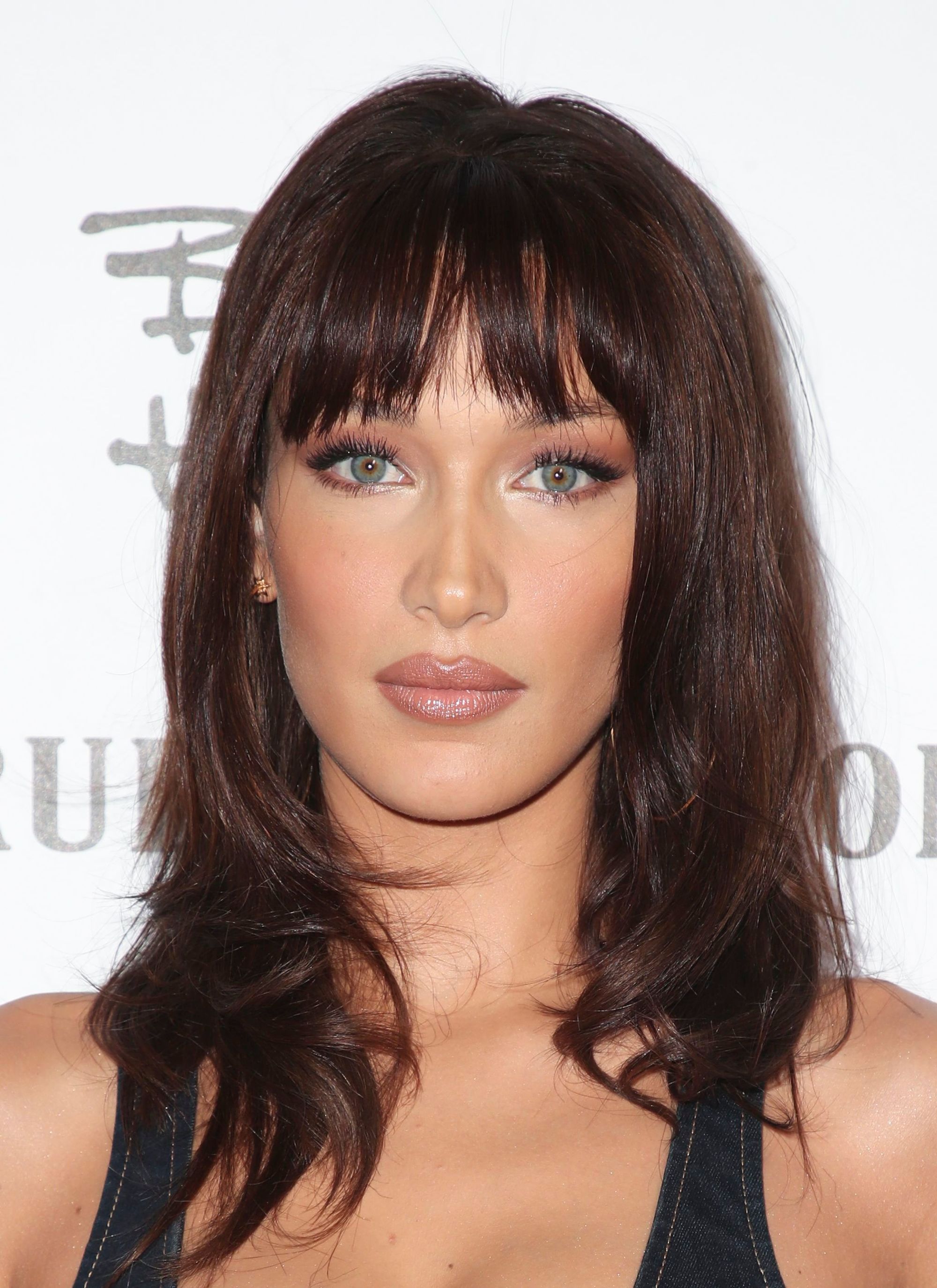 Bella Hadid with shoulder-length '90s-inspired chocolate brown hair styled into a smooth blow out, wearing black and posing on the red carpet