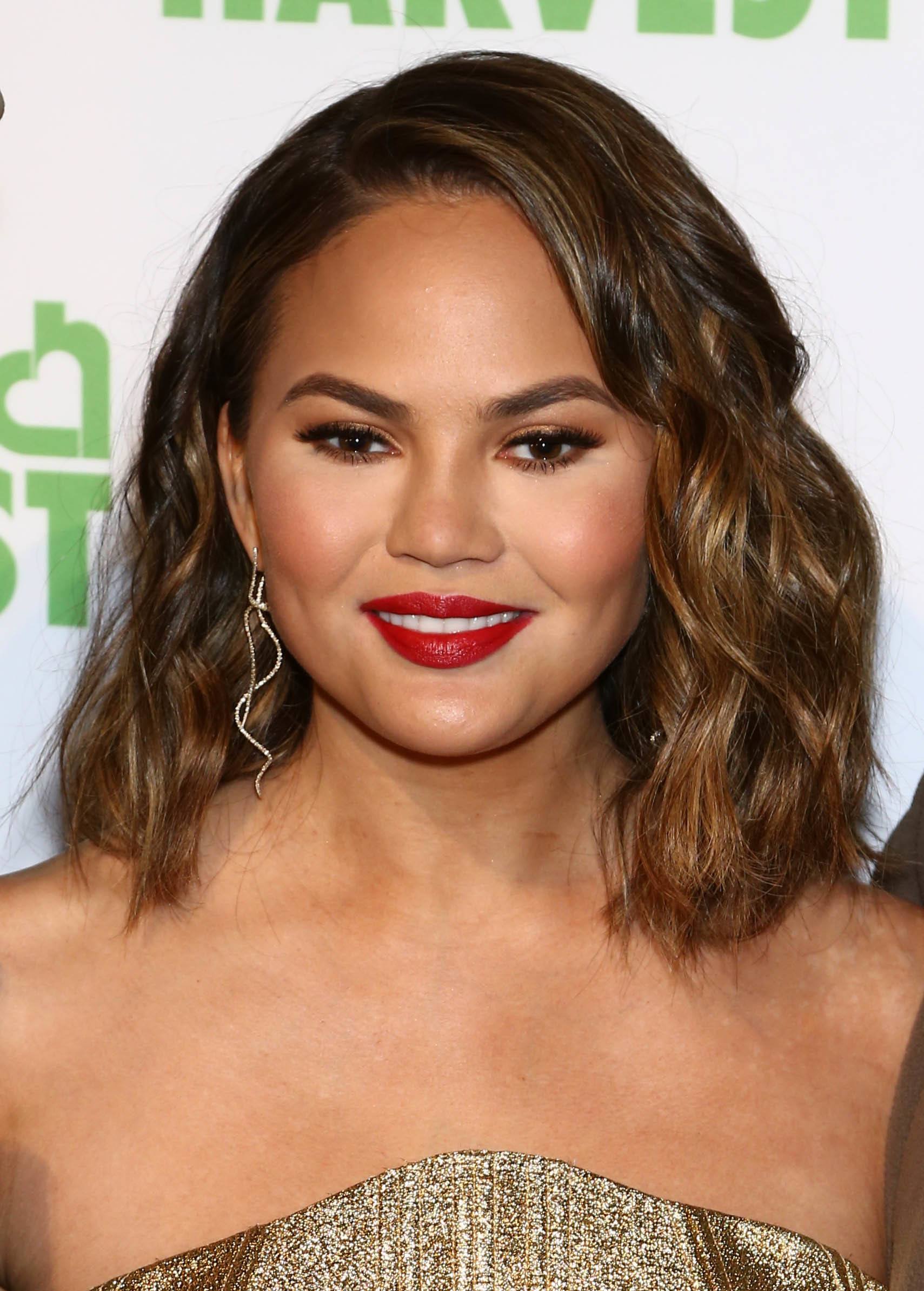 front view of chrissy teigen with dark brown balayage golden brown curly long bob