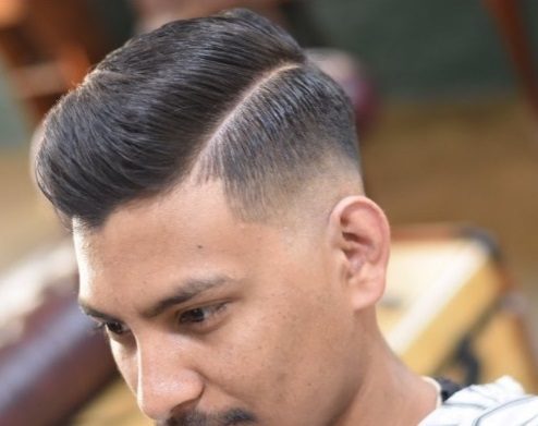 shot from above of a brunette man with a sleek side parted combover hairstyle
