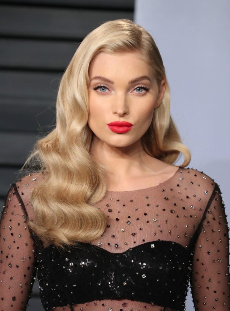 Shades of blonde hair: Elsa Hosk with long wavy champagne blonde hair style in a side parting wearing red lipstick and a black sheer dress.