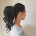 side profile of a brunette woman with long her with her hair in a curly ponytail