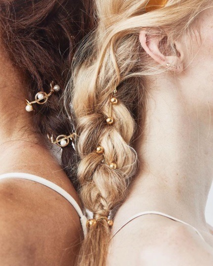 close up shot of a brunette and blonde woman with braided hair with beaded hair accessories woven in