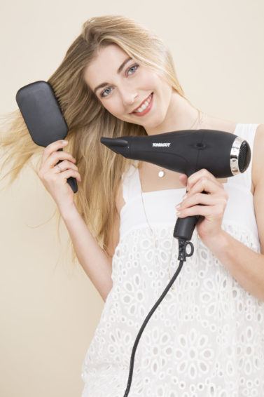 blonde model brushing her hair and drying it with a hairdryer