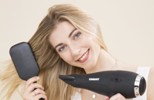 blonde model brushing her hair and drying it with a hairdryer