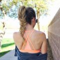 Close up shot of woman with long hair that's been fashioned into high fishtail braided pony, wearing gym clothing