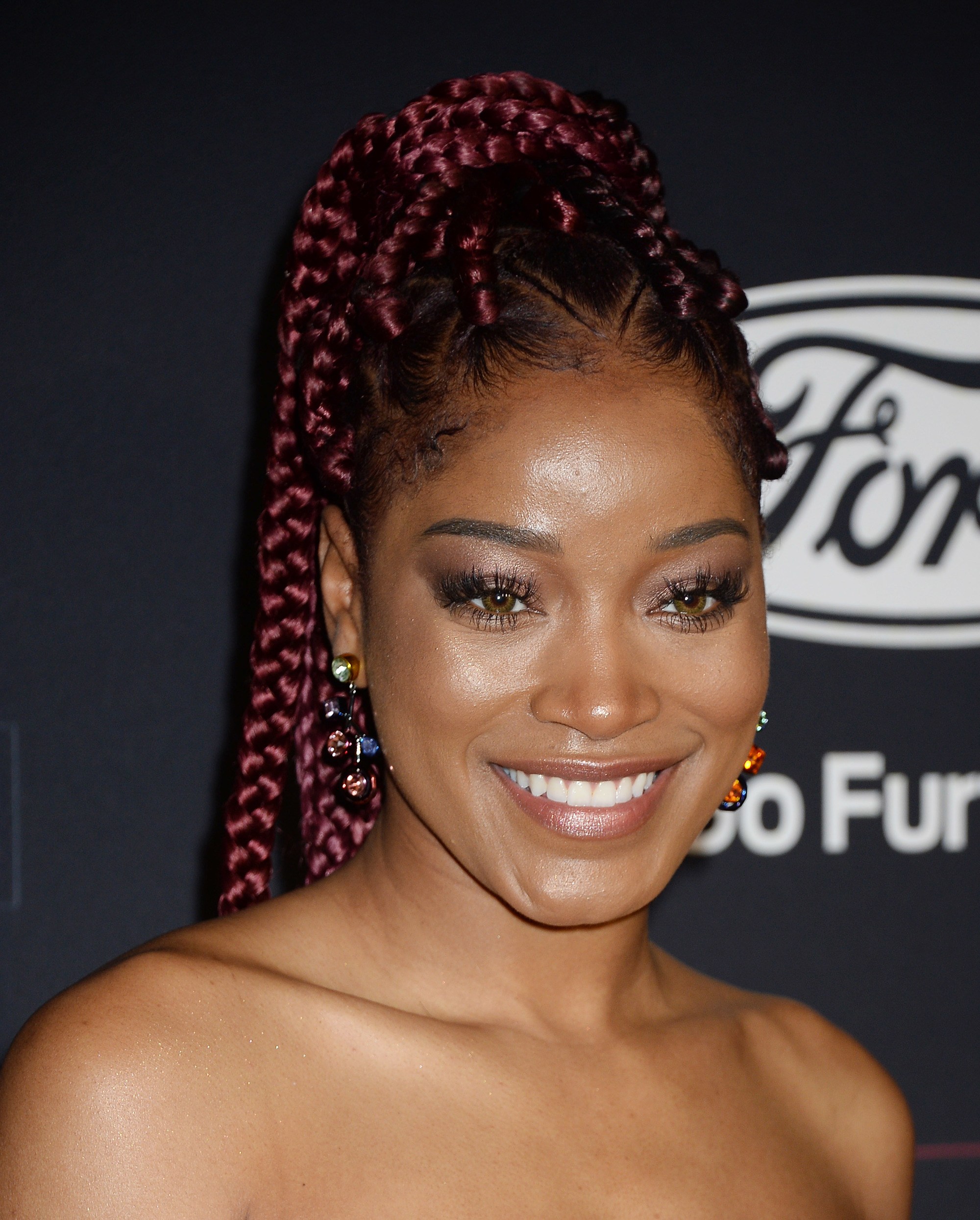 an afro woman with long red braided hair smiling