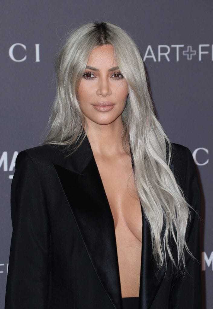 Shades of blonde hair: Kim Kardashian West with very long wavy silver blonde hair wearing a black blazer dress.