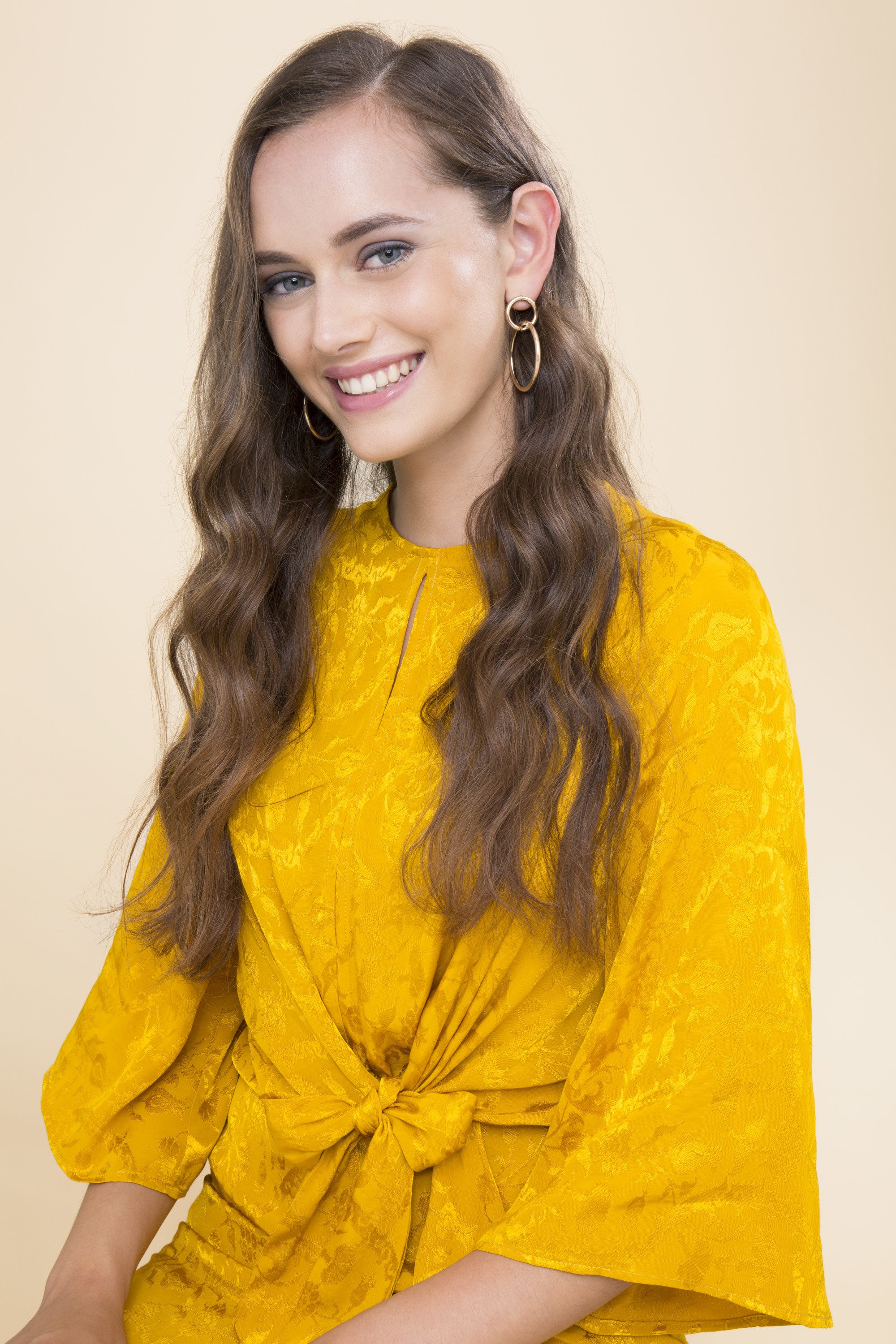 brunette woman in a yellow dress with wavy hair