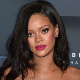 Rihanna with medium length rich natural brown dark hair, with pink lipstick and matching pink dress on the red carpet